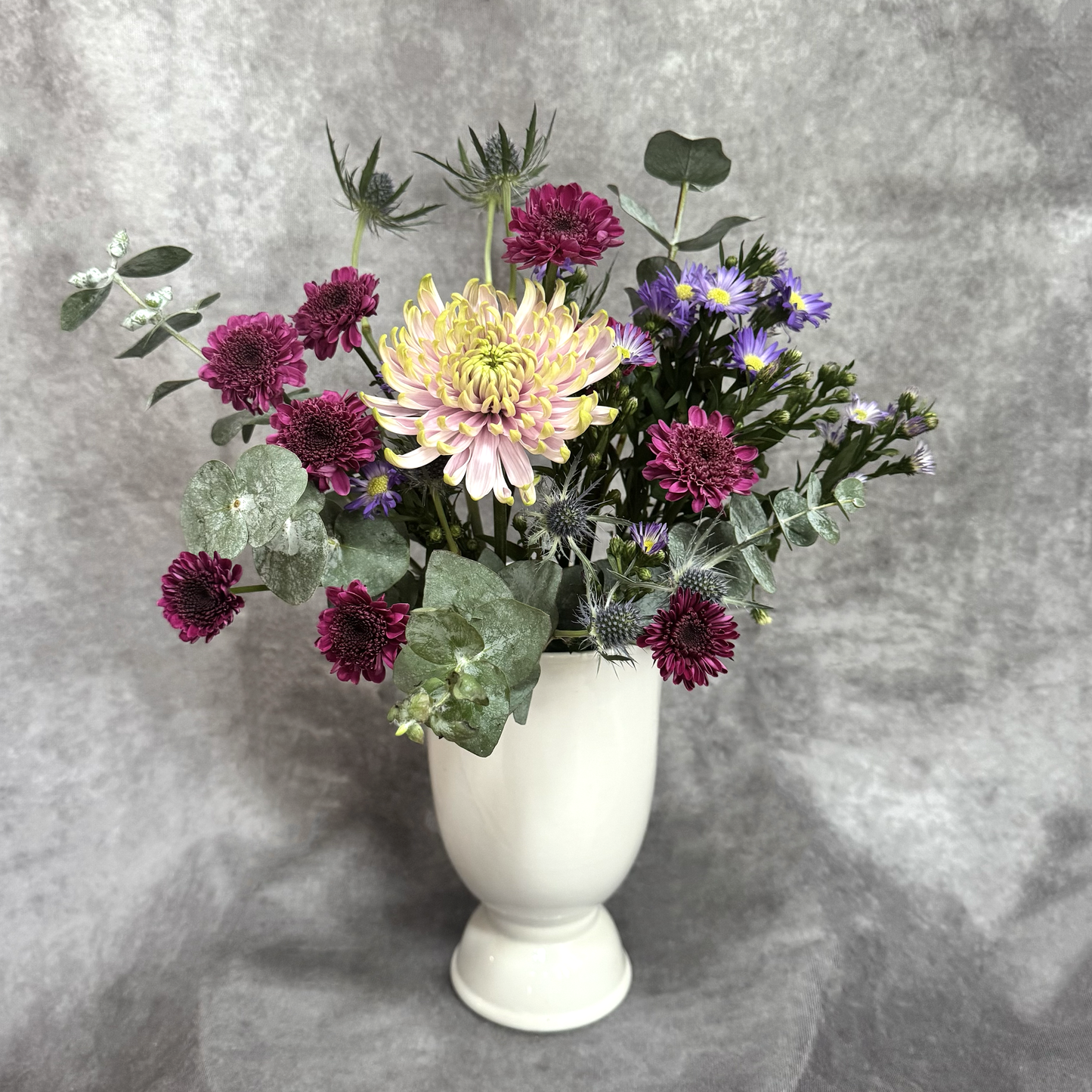 Bouquet of flowers in a white vase against a gray background