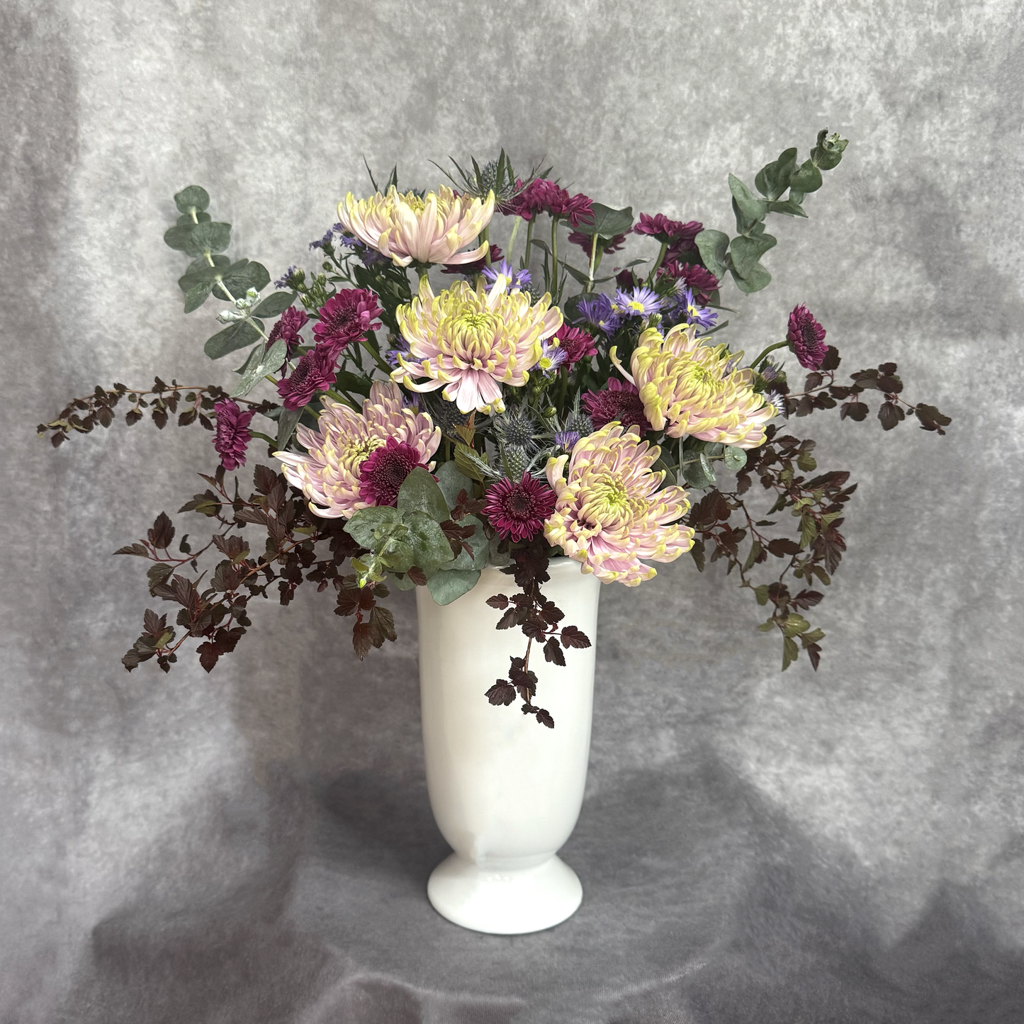 Floral arrangement in a white vase on a gray background