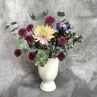 Bouquet of flowers in a white vase against a gray background