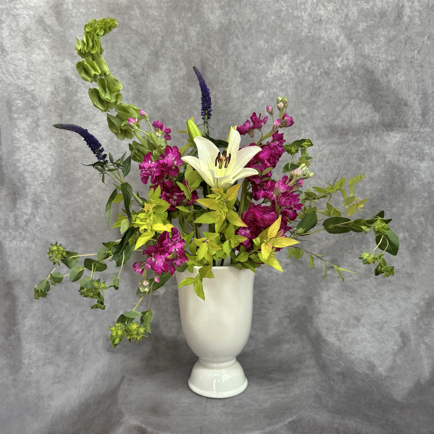 Floral arrangement in a white vase on a gray background