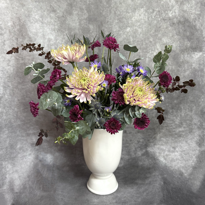 Floral arrangement in a white vase against a gray background