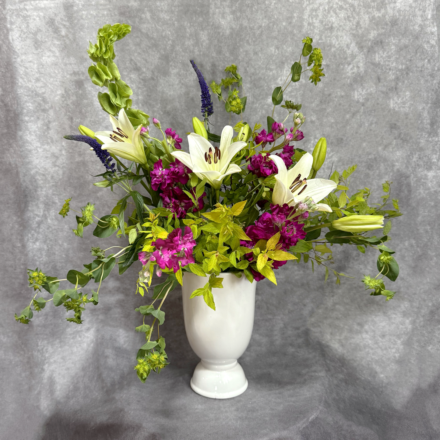 Floral arrangement in a white vase against a gray background