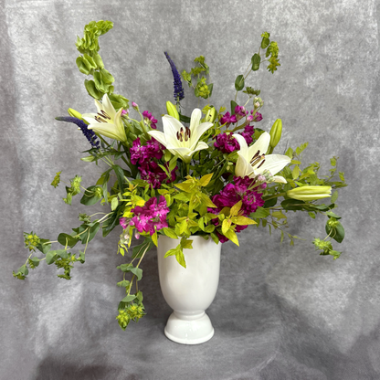 Floral arrangement in a white vase against a gray background