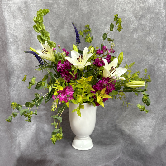 Floral arrangement in a white vase against a gray background