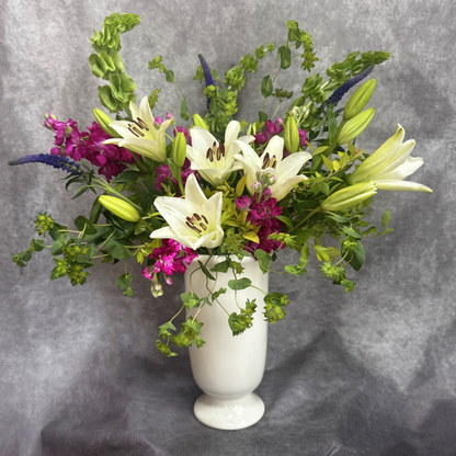 Bouquet of flowers in a white vase against a gray background