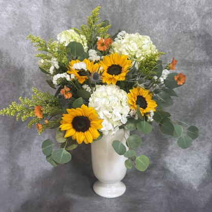 Bouquet of sunflowers and hydrangeas in a white vase on a gray background