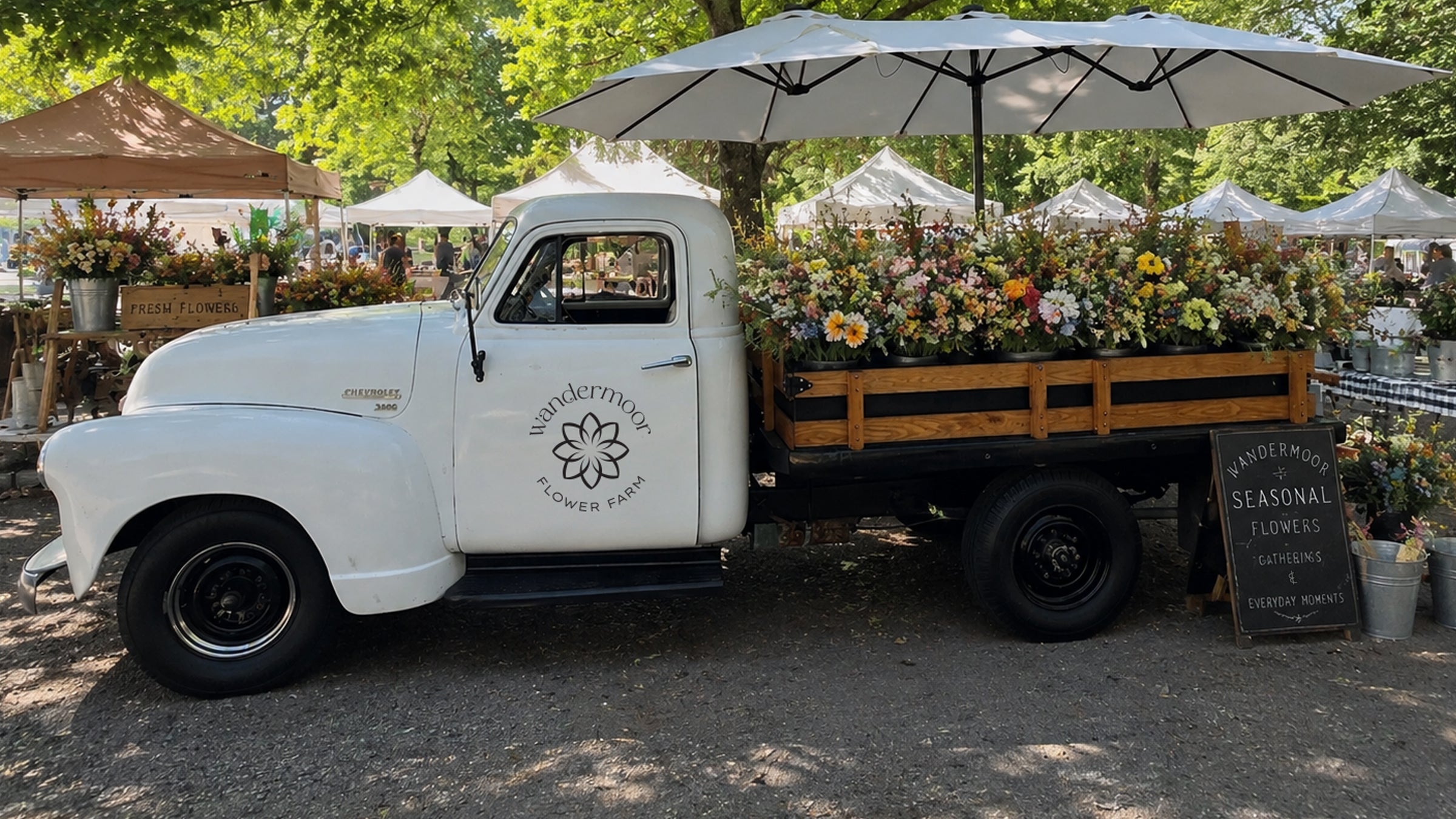 Daisy, our vintage flower truck with 'Wandermoor Flower Farm' logo carrying flowers at an outdoor market.