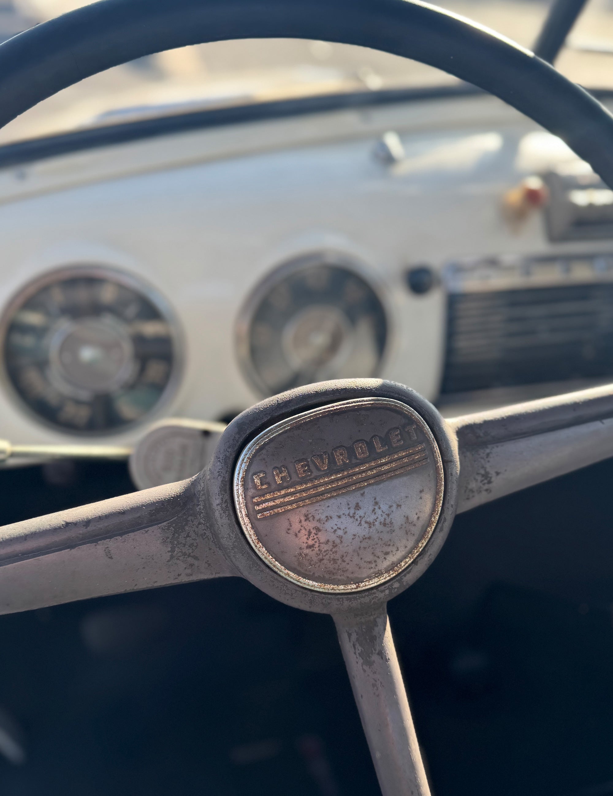 Close-up of a vintgage Chevrolet steering wheel with dashboard in the background